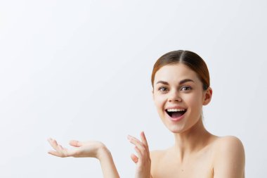 Güzel bir kadın gülümsüyor. Çıplak omuzlar. Temiz cilt cazibesi açık arka plan.