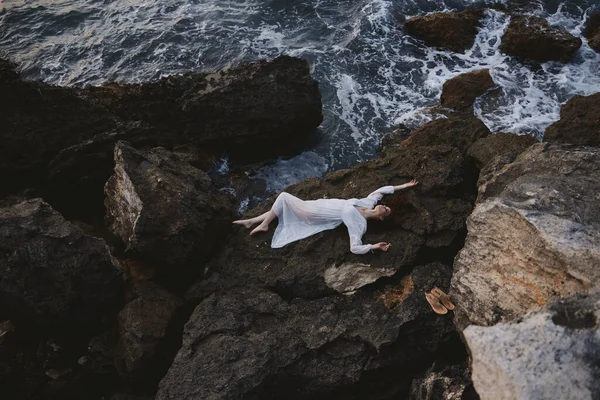 Mujer sensual acostada boca arriba en una vista rocosa de la orilla del mar desde arriba — Foto de Stock