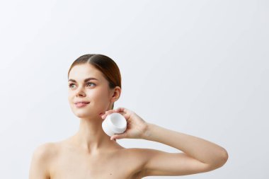 Hafif arka planda vücut kremi olan genç bir kadın. Yüksek kalite fotoğraf