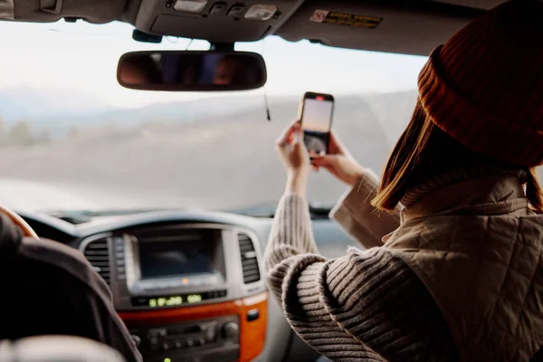 Kobieta z telefonem w ręku robi zdjęcia natury w samochodzie — Zdjęcie stockowe