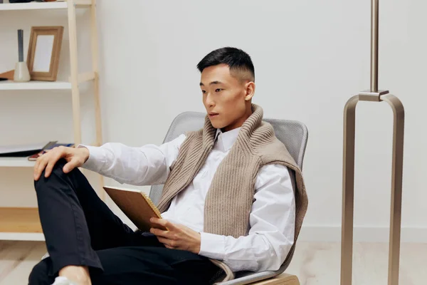 Homem bonito com um tablet senta-se em uma cadeira tecnologias de comunicação — Fotografia de Stock