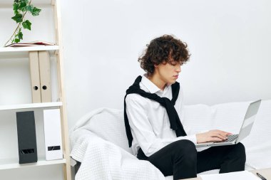 Beyaz koltukta oturan kıvırcık çocuk internetteki eğitim iletişimi.