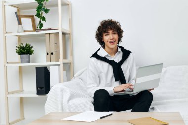 Genç dizüstü bilgisayar beyaz kanepede oturuyor online eğitim iletişimi