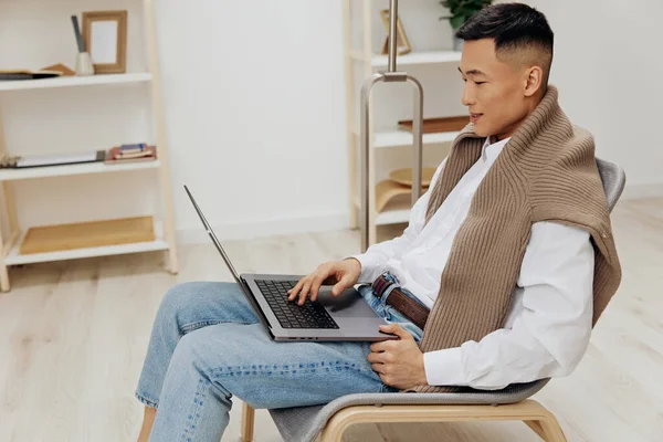 Asiatico uomo su un computer portatile in un sedia in un freelance camera tecnologie — Foto Stock