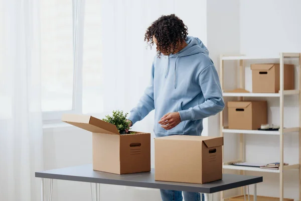 Man met krullend haar uitpakken dingen uit dozen in de kamer sorteren dingen — Stockfoto