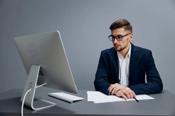 Hommes d'affaires assis à un bureau devant un ordinateur fond gris — Photo