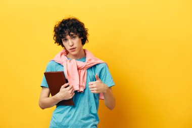 Mavi tişörtlü, not defteri açık manzaralı bir öğrenci.