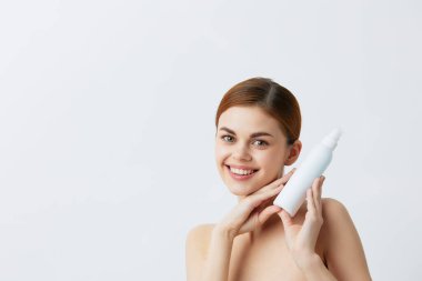 Gri arka planda vücut losyonu olan güzel bir kadın. Yüksek kalite fotoğraf