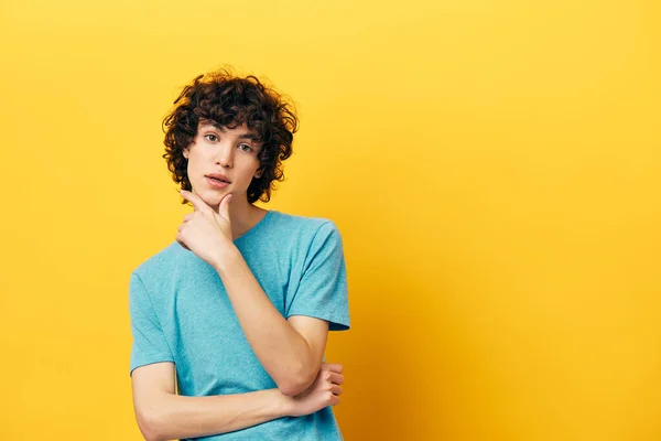 A man with curly hair in a blue t-shirt pensive look — Φωτογραφία Αρχείου