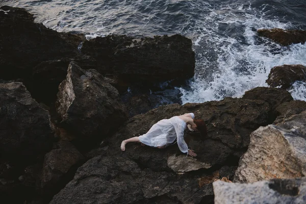 美丽的年轻女子穿着白色的连衣裙 站在荒芜的岩石海岸上的一个僻静的地方 高质量的照片 — 图库照片