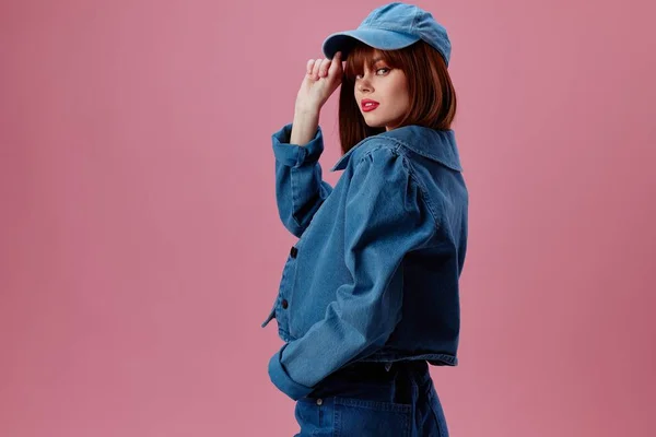 Mujer joven positiva en una gorra y chaqueta de mezclilla posando modelo de estudio inalterado —  Fotos de Stock