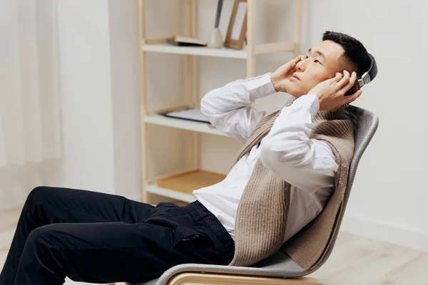 Pria memakai headphone duduk di kursi beristirahat interior — Stok Foto