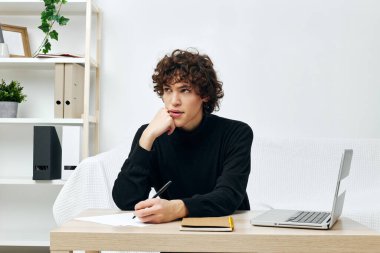 Masadaki kanepede oturan genç bir dizüstü bilgisayarın önünde yaşam tarzı teknolojisi