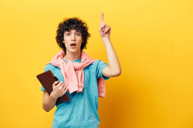 Not defteri sarı arka planda mavi tişörtlü bir öğrenci.