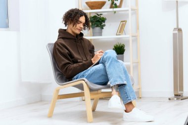 Bir adamın portresi not defterine yazar. Arka planda izole bir odada bir sandalyeye oturur.