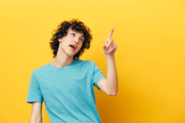 Kıvırcık saçlı mutlu adam sarı arka planı gösteriyor.