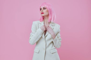 Makyajlı, pembe saçlı, pembe arka planda değişmemiş pozitif bir genç kadın.