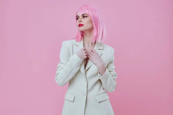 Wanita muda yang positif dalam setelan make up rambut merah muda berpose latar belakang merah muda tidak berubah — Stok Foto