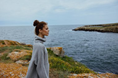 Güzel kadın plaj turizmi bulutlu hava taşlı kıyı rahatlama konsepti