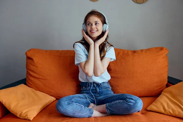 Portrait d'une femme assise sur le canapé à la maison écoutant de la musique sur écouteurs Lifestyle — Photo