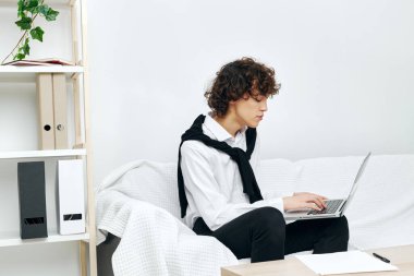 Adam dizüstü bilgisayarı beyaz koltukta oturuyor çevrimiçi yaşam tarzı eğitimi alıyor.