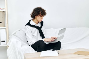 Beyaz koltukta oturan kıvırcık çocuk internetteki eğitim iletişimi.