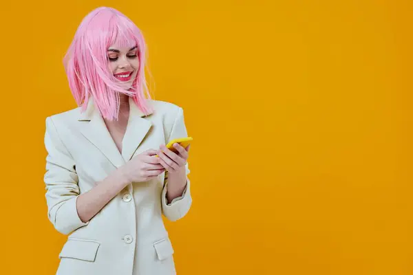 Neşeli, büyüleyici, pembe peruklu kadın telefonda sarı arka planda konuşuyor. — Stok fotoğraf