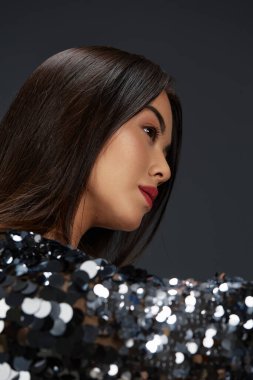 Güzel kadın cazibesi parlak ceket pozu veriyor. Lüks bir arka plan.