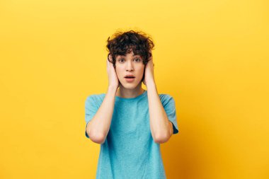 Sarı arka planda kıvırcık saçlı şok olmuş bir adam.