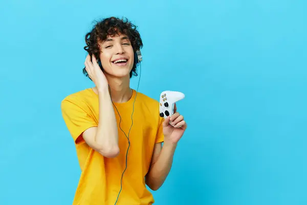 Curly guy plays with joystick in yellow t-shirts technologies — Stock Photo, Image