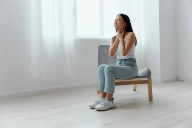 Boğazında şişmiş lenf bezleri var. Acı çeken, bronzlaşmış, güzel bir Asyalı kadın evdeki oturma odasında boğazına dokunuyor. Yaralar Kötü Sağlık Hastalığı konsepti. Güzel teklif Banner.