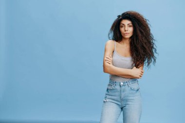 Havalı kotlar teklif ediyor. Göğsünde Afrika haçı olan seksi Latin kadın, kameraya bak. Moda. Stüdyo çekimi mavi gökyüzü arka planında. Boşluğu kopyala, tasarım reklamı için boş yer