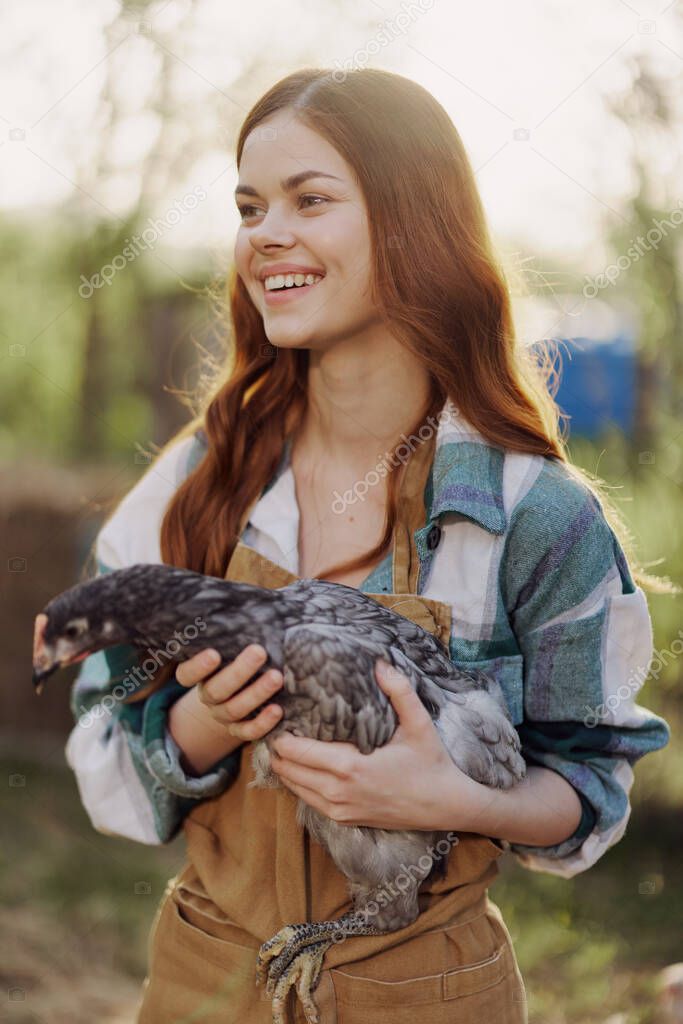 A happy young woman smiling and holding a young chicken that lays eggs for her farm. High quality photo