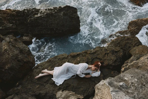 美丽的女人躺在岩石海岸上 岩石表面的裂缝不变 高质量的照片 — 图库照片