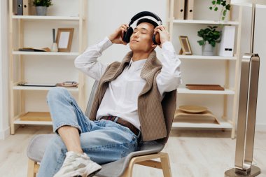 Genç süveter omuzlarda kulaklıklar odada yaşam tarzında müzik çalıyor. Yüksek kalite fotoğraf