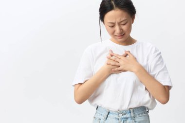 Kalp krizi geçirdi. Acı çeken bronz tenli genç Asyalı kadın beyaz arka planda yalnız poz vererek ağlayarak elini göğsüne koydu. Yaralar Kötü Sağlık Hastalığı konsepti. Güzel teklif Banner.