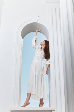 Beyaz elbiseli bir kadın pencere aralığında poz veriyor. Yüksek kalite fotoğraf
