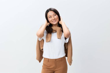 Bej renkli, sıcak kazaklı, gülümseyen Koreli genç bir bayan beyaz stüdyo arka planında yalnız poz veriyor. Reklam için en iyi teklif. Sonbahar tarzı konsept. Mevsimlik Satış