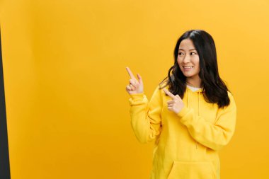 Bana bak. Sarı kapüşonlu kapüşonlu, neşeli, sevimli Asyalı genç bayan fotokopi odasının arka planında izole bir şekilde poz veriyor. Güzel teklif. Halkın Duyguları kavramı