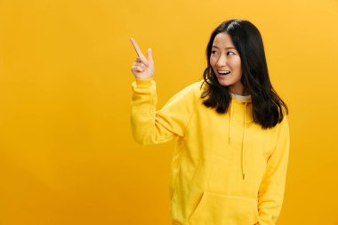 Bana bak. Sarı kapüşonlu kapüşonlu, neşeli, sevimli Asyalı genç bayan fotokopi odasının arka planında izole bir şekilde poz veriyor. Güzel teklif. Halkın Duyguları kavramı