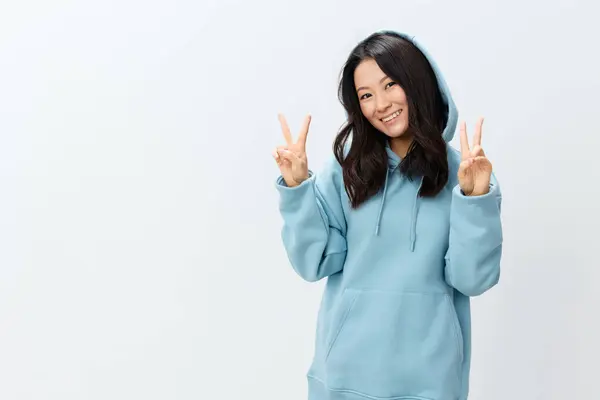 身穿蓝色连帽衫的快乐可爱的漂亮的亚洲年轻女性在白色的工作室背景上摆出孤立的手势 最好的广告报价 时装新品系列广告概念 — 图库照片