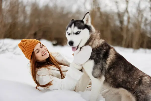 在雪地里和狗玩耍的年轻女人友谊生活方式 高质量的照片 — 图库照片
