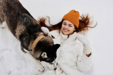 Karda mutlu genç bir kadın köpekle oynuyor. Eğlenceli bir arkadaşlık havası. Yüksek kalite fotoğraf