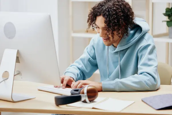 handsome guy in a blue jacket in front of a computer with phone Lifestyle. High quality photo