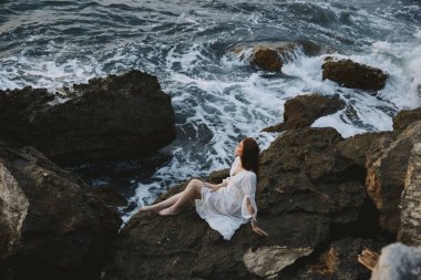 Uçurum dalgalarının bulutlu havasında gelinlikli çıplak ayaklı kadın. Yüksek kalite fotoğraf