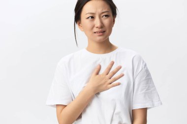 Kalp krizi geçirdi. Acı çeken bronz tenli genç Asyalı kadın beyaz arka planda yalnız poz vererek ağlayarak elini göğsüne koydu. Yaralar Kötü Sağlık Hastalığı konsepti. Güzel teklif Banner.