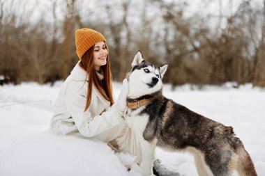 Kışın bir tarlada bir köpekle yürüyüş yapan neşeli bir kadın. Yüksek kalite fotoğraf