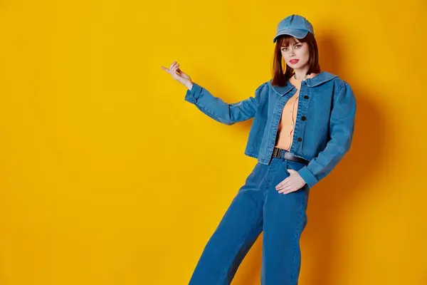 Beauty Fashion woman in a cap and denim jacket posing yellow background unaltered. High quality photo