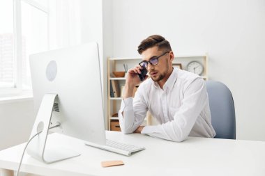 Beyaz gömlekli işadamları bilgisayar başında bir telefon yöneticisiyle oturuyor. Yüksek kalite fotoğraf