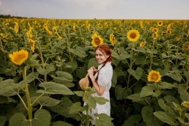 Beyaz elbiseli, iki örgülü şapkalı kadın kırsal kesimde ayçiçeği tarlası. Yüksek kalite fotoğraf